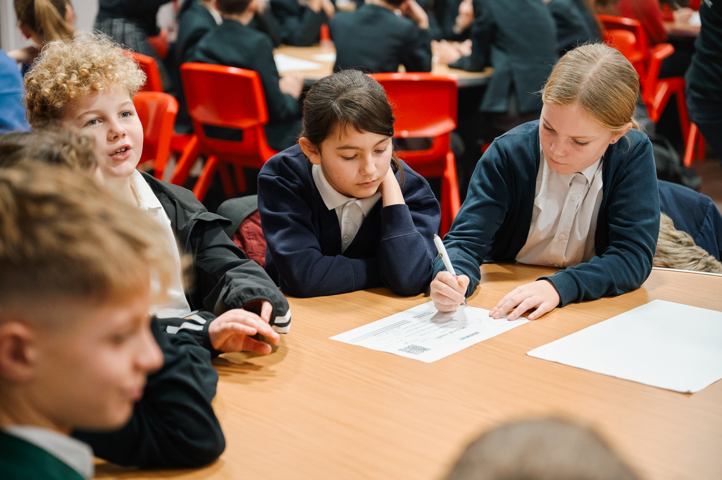 A group of school children discussing events and making notes.