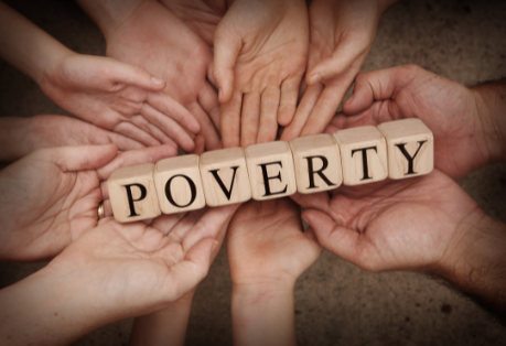 Hands holding the word poverty on cubes.