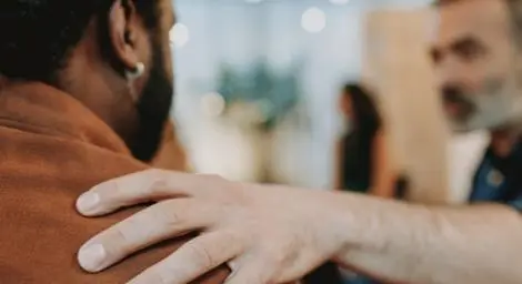 Man holding another man's shoulder offering support