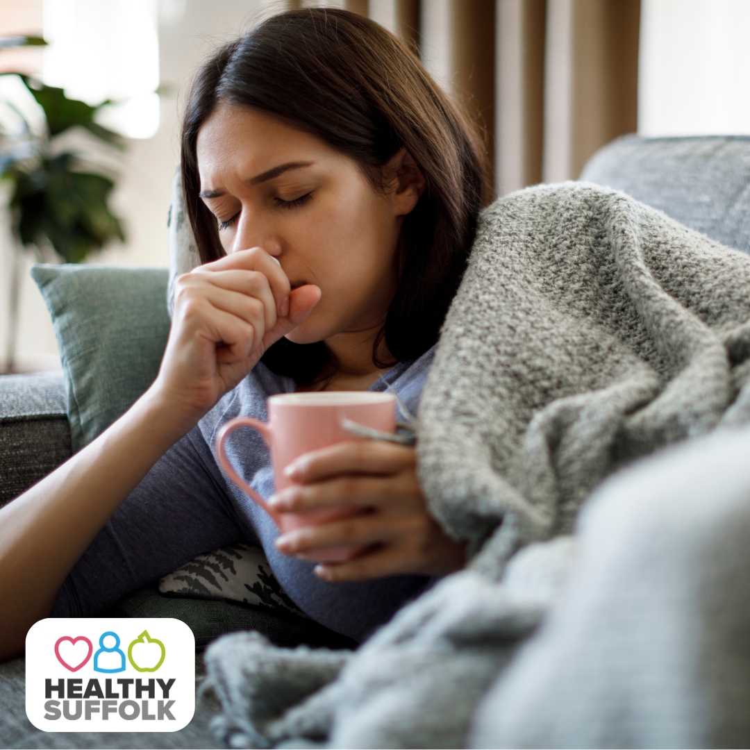 Women holding a warm drink and covering her mouth as she coughs